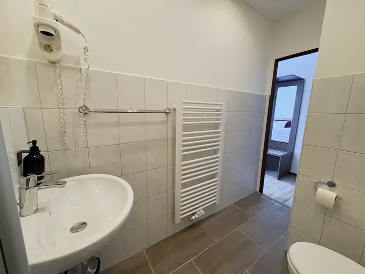 Bad mit Waschbecken, Föhn und Handtuchheizkörper, Blick ins Zimmer