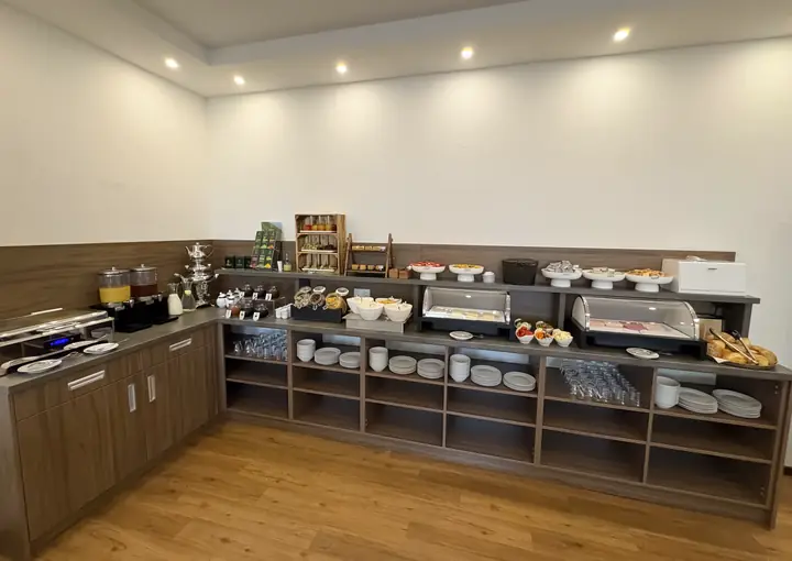 Die ganze Buffetzeile im Frühstücksraum: Warmhaltebehälter, Getränke, Geschirr und Brotkorb