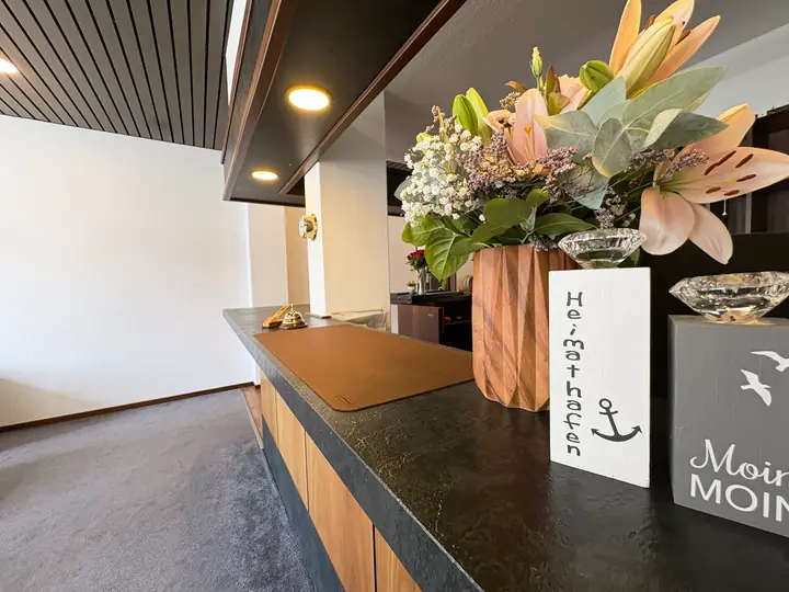 Rezeptionstresen mit Blumen und Moin-Schild
